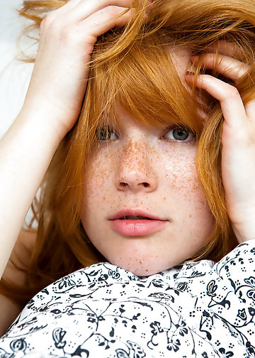 Redhead with freckles removes her lingerie and sits on the bed
