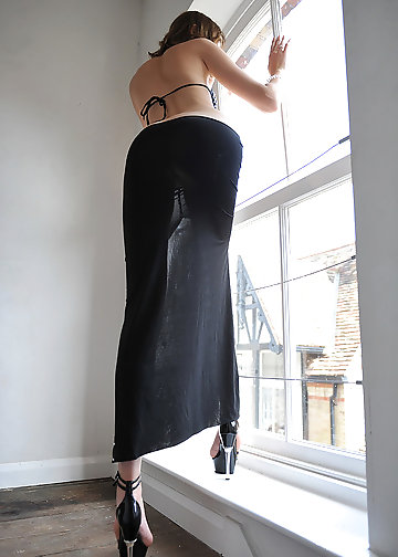 Sexy nude babe leans onto a big window and plays with herself