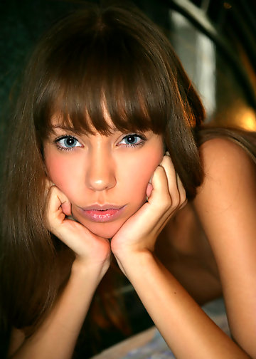 Girl with dark hair turns from side to side to flaunt boobs in bed