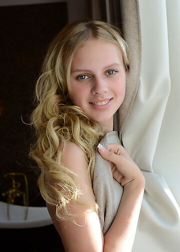 Splendid blonde with curly hair willingly shows naked body before taking a bath