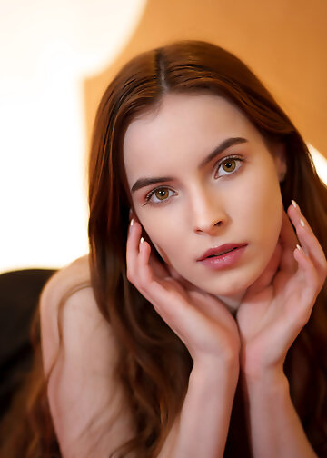 Beautiful redhead lady in black dress posing nude on red sofa