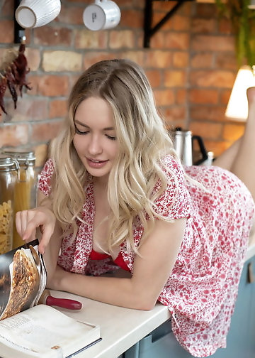 Russian blonde with blue eyes smiles undressing in the kitchen