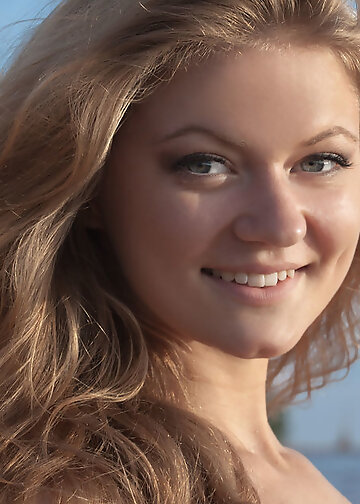 Natural sweetheart in pink dress smiles mischievously on the seaside
